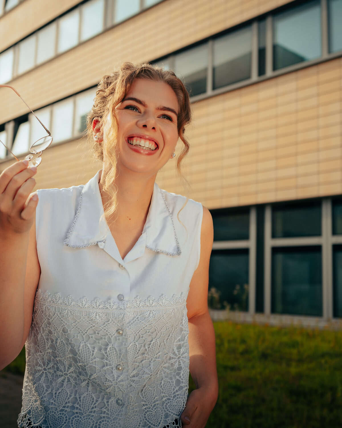 Annie im Freien, lachend, Brille in der Hand